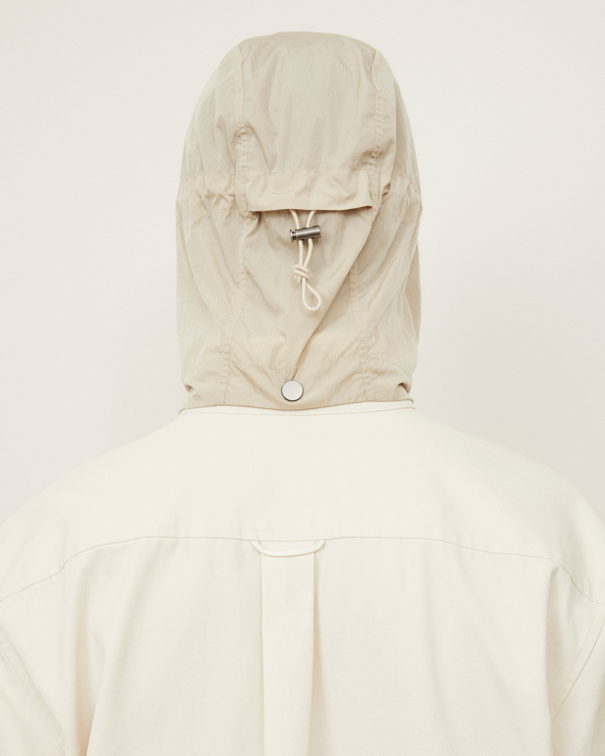Back view of the MORROW Canvas Shirt Jacket in natural, featuring the Fly Anorak Hood in bark. Photographed in Australia to highlight the jacket’s refined construction and functional detailing.